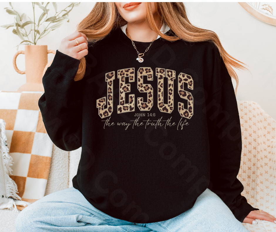 Person wearing a black sweatshirt with 'JESUS' text in leopard print and white lettering.